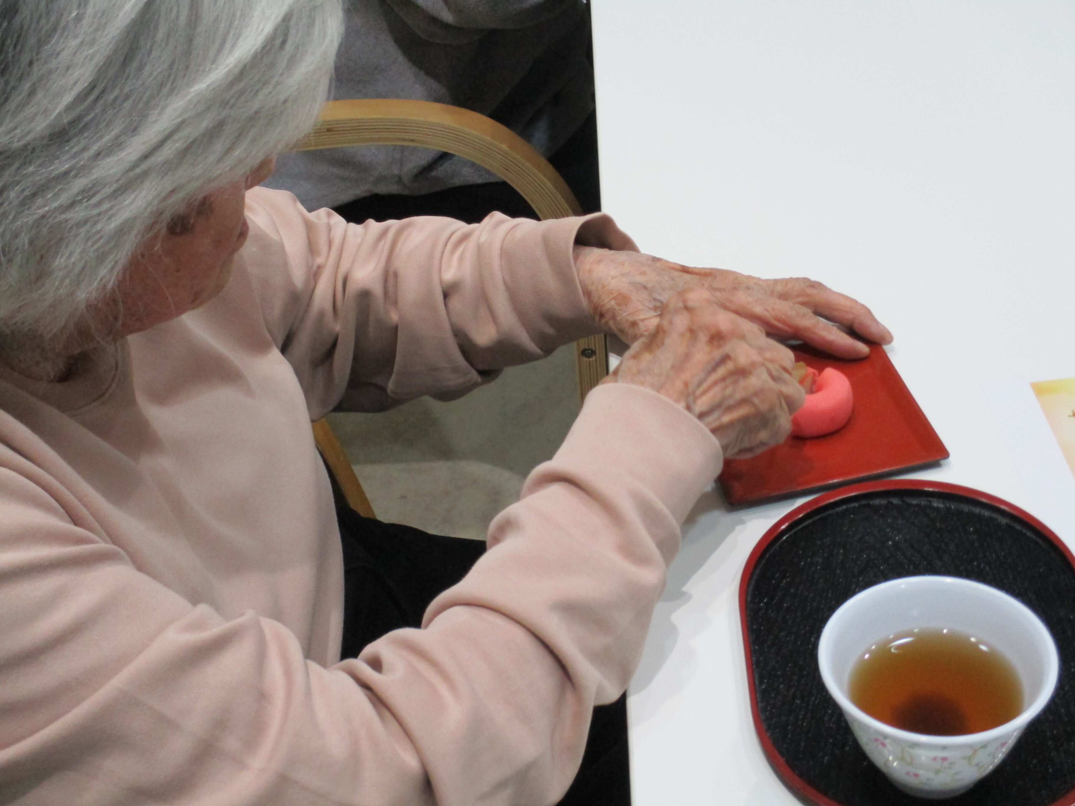 高齢女性が和菓子を切る様子のお写真