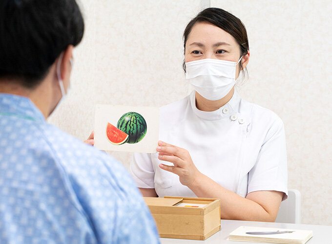 病院の廊下で車椅子患者を押す看護師の写真